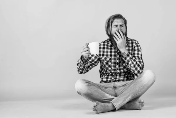 yawning sleepy tired guy. he is taking a coffee break. Handsome mature guy drinking from cup. Hold cup of coffee or tea. lifestyle concept. handsome hipster man with cup of coffee.
