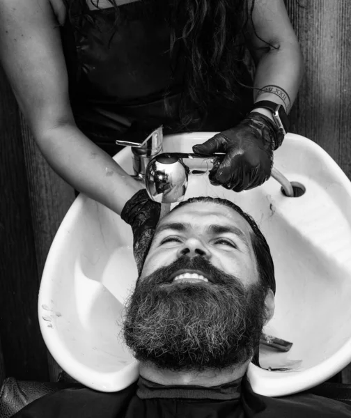 bearded man. hair and beard care. confident and handsome brutal man. grooming hair in barbershop. male beauty and fashion. making new hairstyle. female hairdresser in workshop.