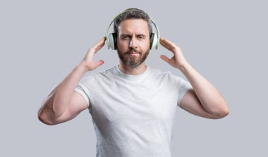Kulaklıkla müzik dinleyen bir adamın fotoğrafı. Gri arka planda izole edilmiş kulaklıkla müzik dinle. Adam stüdyoda kulaklıkla müzik dinliyor. Modern kulaklıkla müzik dinle..