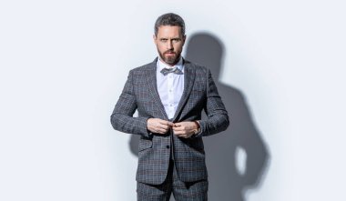 Karizmatik adam smokin giyer. Gri arka planda smokinli adam. Stüdyodaki smokinli adam. Smokin giyen adamın fotoğrafı..