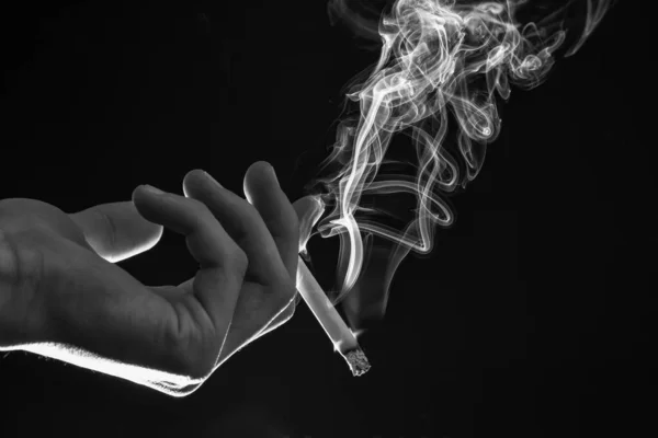 Mężczyzna Ręka Trzymać Palenie Papieros Strumień Dymu Ciemne Tło Zły — Zdjęcie stockowe