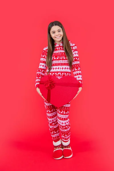 new year. positive teen girl with red new year present in studio. teen girl hold new year present standing isolated on red background.