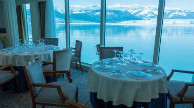 Seyahat güzergahında kimse yok. Manzaralı buzul körfezi manzarasının panoramik pencerelerinin yanındaki boş restoran koltukları. Doğal parktaki dağ buzulu restoranı. Hubbard Buzul Restoranı.