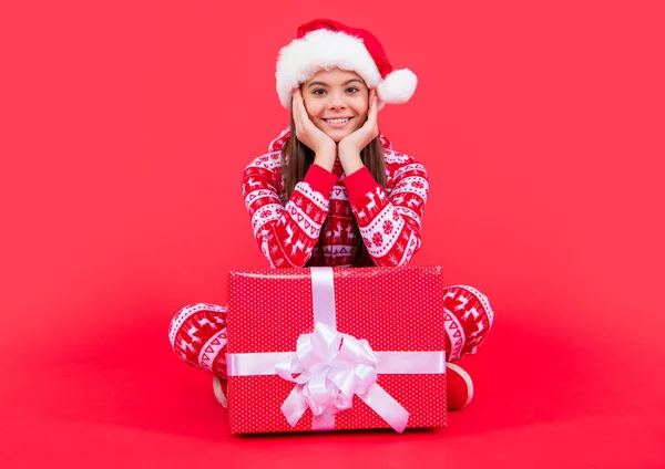快乐的圣诞节 快乐的圣诞老人少女坐在演播室里 少女带着圣诞圣诞礼物 红底孤身一人 — 图库照片