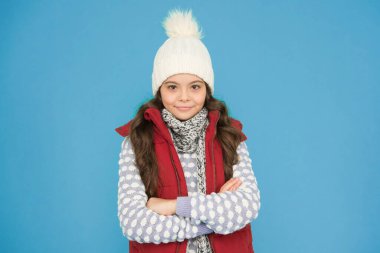 Tatile hazırım. Uzun kıvırcık saçlı, örgü şapkalı bir çocuk. Soğuk sezon tarzı Noel aktivitesi. çocukluk mutluluğu. Termal giysi. Mutlu genç kız kalın kıyafetler giyer. Kış çocuğu modası.