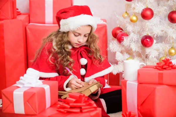 I was good girl all year. Child write letter to santa claus. Child santa costume believe in miracle. Letter for santa. Wish list. Girl little kid hold pen and paper near christmas tree writing letter.