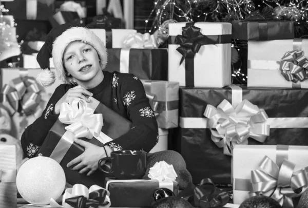 レジャーやアクティビティ ボクシングの日だ かわいいサンタさんに興味津々 子供の幸せな男の子はクリスマスツリーの近くのギフトを見つける ギフトショップ キッズサンタ帽子クリスマスギフトボックス メリークリスマス 冬の美しさ — ストック写真
