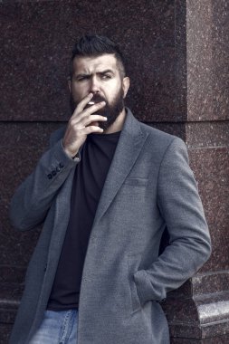Erkek kötü alışkanlıkları. Bağımlılık. Modern hayatta gündelik moda. Kendine güvenen ve yakışıklı vahşi bir adam. Duman. Sakallı hippi sigara içiyor. Bıyıklı, vahşi, beyaz bir hippi. Havalı ve şık..