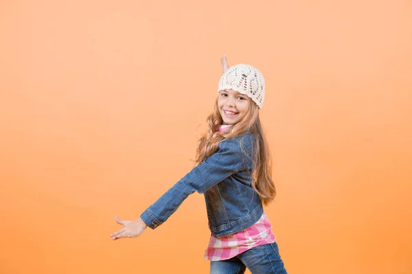 ジーンズのスーツ オレンジ色の背景に格子縞のシャツの子 長いブロンドの髪笑顔とポーズで女の子 幸せな子供時代のコンセプトです 美しさ ファッション スタイル トレンド コピー スペース — ストック写真
