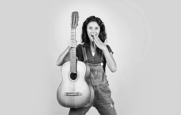 cheerful lady in shirt denim style play the guitar on blue background, music.