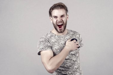 Kızgın yüz ve şık saç, saç kesimi sakallı maço. Tshirt gri arka plan üzerinde adam. Kuaför Salonu, berber. Damat, erkek güzellik kavramı. Moda, Stil, eğilim, kopya alanı