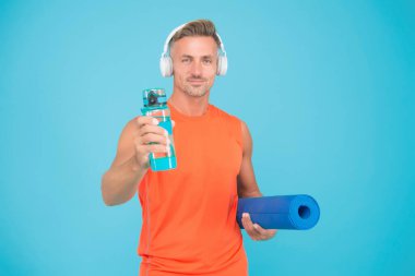 Sağlık önceliklidir. Sağlıklı bir adam yoga eğitimi için su tutar. Spor salonu koçu mavi arka plan. Su ve hidrasyon. Sağlık sigortası. Su seviyesi ve sağlık düzeyi artıyor. Sadece sağlık alışkanlığı..