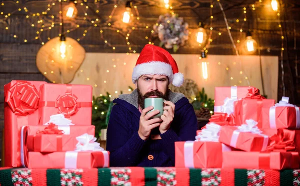 茶时间 男人带着胡子的圣塔克洛斯帽喝着热饮料 多姿多彩的新年啊很多礼物 用缎带和蝴蝶结包裹礼物 希斯特为家人准备了礼物 寒假快乐热身 — 图库照片