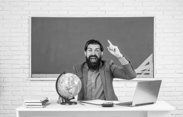 college lecturer on geography lesson. back to school. informal education. happy inspired mature teacher looking at globe. bearded man geographer work in classroom with map. prepare for exam.