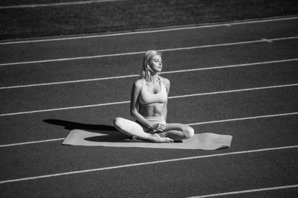 フィットネストレーニング前に陸上競技場でヨガを練習しているスポーツウェアの女性 — ストック写真