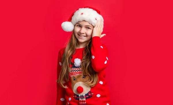 笑顔のティーンの女の子は夏休みにセーターとサンタの帽子を着用します メリー クリスマス サンタ クラスの面白い10代の女の子赤いクリスマスの背景に帽子 サンタ ハットのクリスマス ティーンの女の子 — ストック写真