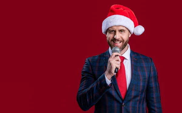 happy new year. businessman presenter at new year isolated on red banner. new year businessman presenter. new year businessman presenter in santa hat. businessman presenter with microphone.