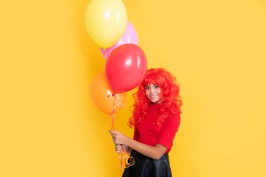 Sarı arka planda parti balonu olan gülümseyen çocuk..