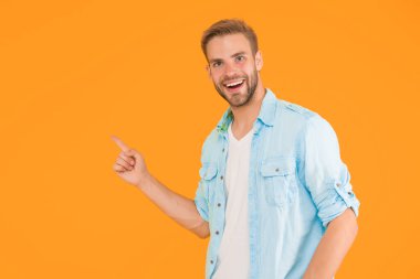 Fotokopi çekilen yeri işaret eden şık, mutlu bir adam sarı arka plandaki günlük gömlekle reklam için, ürün sunuyor..