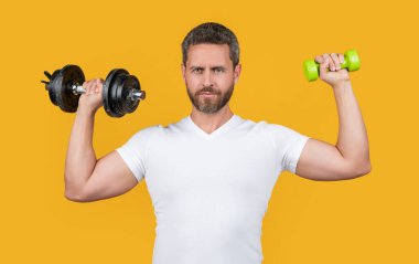 Stüdyoda dambılla güçlü bir sporcu eğitimi. Dambılı tişörtlü güçlü bir sporcu eğitimi. Dambıllı güçlü bir sporcu eğitimi. Sarı halterli güçlü sporcu eğitimi.