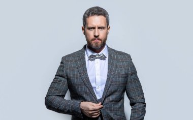 Smokin giyen bir adamın portresi. Smokinli adam gri arka planda izole edilmiş. Stüdyodaki smokinli adam. Smokin giyen adamın fotoğrafı..