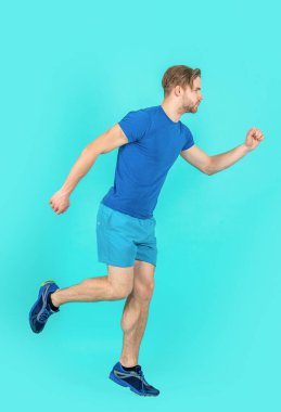 Spor adamı mavi arka planda izole edilmiş egzersiz yapıyor. Spor adamı stüdyoda koşuyor. Spor adam spor kıyafeti giyerek egzersiz yapıyor. Spor yapan adamın tam boy fotoğrafı..