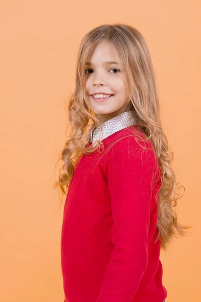 Dziecko Kręcone Blond Włosy Czerwonym Swetrze Dziewczyna Uśmiech Pomarańczowym Tle — Zdjęcie stockowe