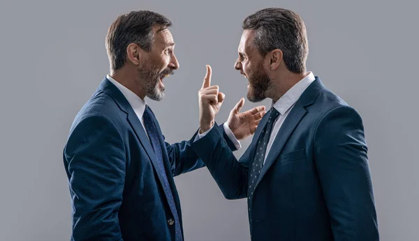 stock image arguing businessmen shouting. photo of businessmen arguing with anger. two arguing businessmen isolated on grey background. businessmen arguing in studio.