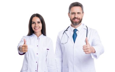 Terapist doktor ve hemşire baş parmağını beyazın üstünde gösterdi. Stüdyoda doktor ve hemşire. Terapist doktor ve hemşirenin fotoğrafı beyaz önlük giyiyor. Doktor terapist ve steteskoplu hemşire..