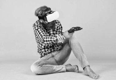 Oyunu oyna. Adam VR kulaklık takarak tecrübe kazanıyor. Sakallı hippi modern teknoloji kullanır. Oyun konsolu. Sanal gerçeklik gözlüklü bir adam. Geleceğin teknolojisi. Görsel gerçeklik kavramı.