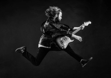 Rock müzik çalıyordu. Modaya uygun çılgın adam. müzik enstrümanı. Deri ceketli duygusal sakallı rockçı. Uzun saçlı bir adam elektro gitar çalıyor. Rock müzik tarzı. müzisyen gitarist atlıyor.