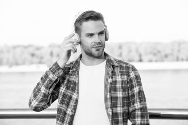 Kareli gömlekli yakışıklı, traşsız adam kulaklıkla müzik dinliyor, modern hayat..