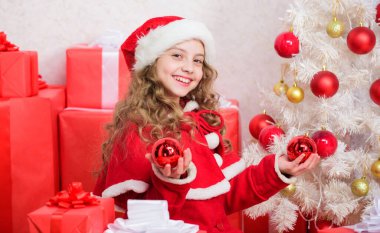 Noel arifesi kavramı. Noel kutlamalarına katılın. Noel ağacının yanında mutlu bir Noel Baba var. Çocuk Noel ağacı süslemesi yapıyor. Sevgi dolu tatil aktiviteleri. Çocuk geleneğin tadını çıkarıyor.