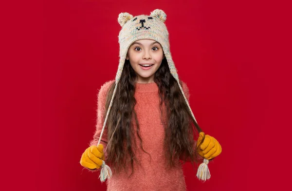 赤い背景に隔離された耳フラップの帽子を被った白人の10代の子供 スタジオでは10代の子供がセーターとイヤーフラップの帽子を着ています 10代の子供の冬のファッション イヤーフラップ ハット ニットウェア イヤーフラップハットの10代の子供モデル — ストック写真