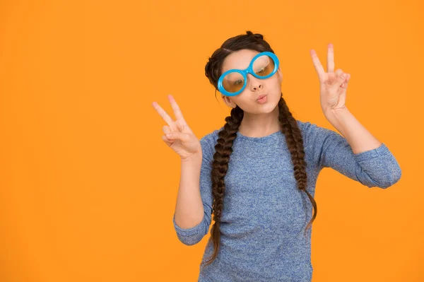 showing piece gesture. kid fashion and beauty. small girl looking cool. childhood happiness. beautiful braided long hair. stylish braids and pigtails. party fun. funny teenage girl in glasses.