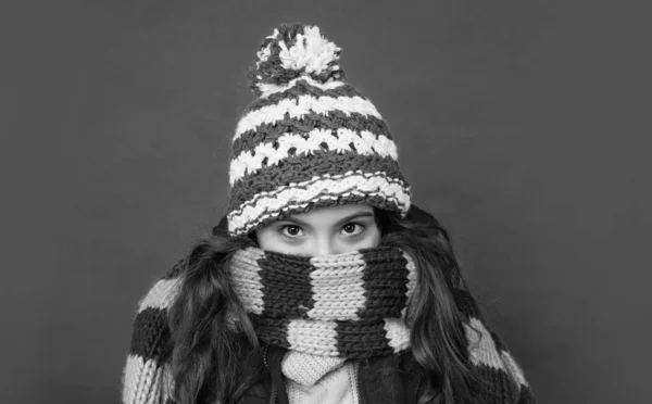 teen girl in knitted winter hat wear scarf on red background, cold weather.