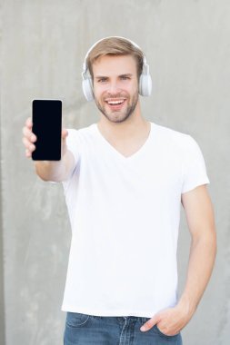 Mutlu adam sunar. Müzik uygulaması, kopyalama alanı. Adam dışarıda müzik uygulamasını sunuyor. Adam akıllı telefondan müzik uygulamasını sunuyor. Kulaklıkla müzik uygulaması sunan bir adamın fotoğrafı.