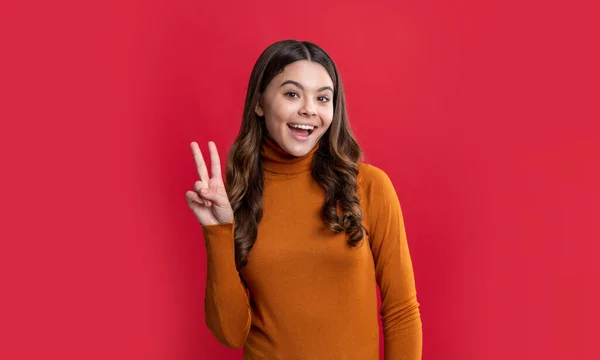 teen girl portrait show peace isolated on red background. portrait of teen girl in studio. portrait of young teen girl. photo of teen girl portrait with brunette hair.