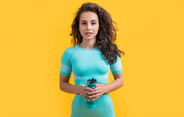 健身女运动员带着运动瓶在演播室里 健美的女运动员拿着用黄色背景隔开的运动水合物瓶 健身和运动体液补充 — 图库照片