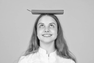 Sarı arka planda okul kitabı olan neşeli çocuk, know leldge.