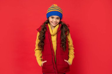 Olumlu duygularını ifade et. Kış modası. Şapkalı, kıvırcık saçlı, gülümseyen çocuk. Kadın manken. Yelekli genç kız. Kalın giysiler giyen çocuk portresi.