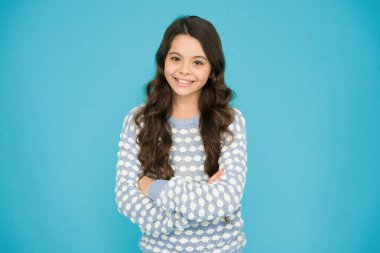 Daha güzel görün. Güzel ve mutlu çocuk mavi arka plana bak. Uzun dalgalı saçlı, moda görünümlü küçük bir kız. Şirin bir manken. Vogue bakışı. Moda ve güzellik. Kuaför salonu..