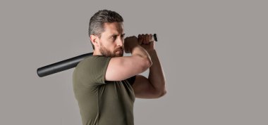 Kızgın adam tehdit ediyor ve vuruyor. Öfkeli adam, gri arka planda izole edilmiş yarasayla öfkesini ifade eder. Stüdyoda beysbol sopasıyla öfkeli bir adama saldırmak. Kızgın adamın fotoğrafı. Sopayı tut..