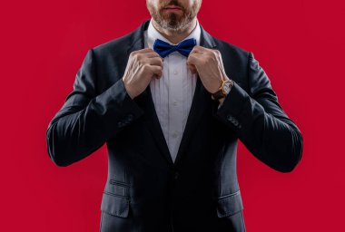 Stüdyoda smokin giyen adamı gördüm. Smokin giyen bir adamın fotoğrafı. Adam smokin resmi takım elbise giyiyor. Smokinli adam kırmızı arka planda izole edilmiş..