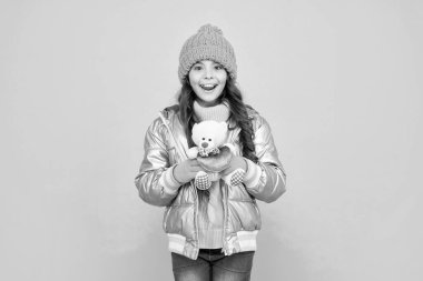 Sevgililer Günü için aşk oyuncağı. Kabarık ceketli ve şapkalı hayret verici çocuk. çocukluk. Genç kız oyuncak ayıyı tutuyor. Mavi arka planda kalın giysiler giyen bir çocuk. Olumlu duygularını ifade et. kış modası.