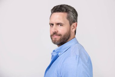 Stüdyoda sakallı, olgun bir adamın portresi. Sakallı, olgun bir adamın fotoğrafı. Kirli sakallı, normal gömlekli olgun bir adam. Gri arka planda sakallı, olgun bir adam..