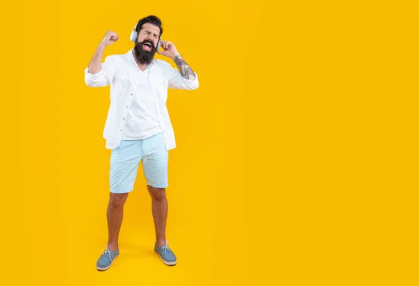 listen to music concept. studio shot of shouting man with headphones. cool man listening music. bearded man listening music in headphones isolated on yellow. man listening music in headphones.