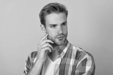 Düşünceli yüzlü, sarı arka planda düşünen ciddi bir gencin portresi..