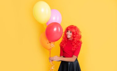 Sarı arka planda parti balonu olan neşeli çocuk..