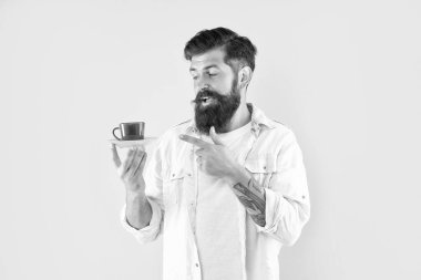 Sakallı hippi parmağıyla sarı arka planda kahve fincanı, kahve fincanı..